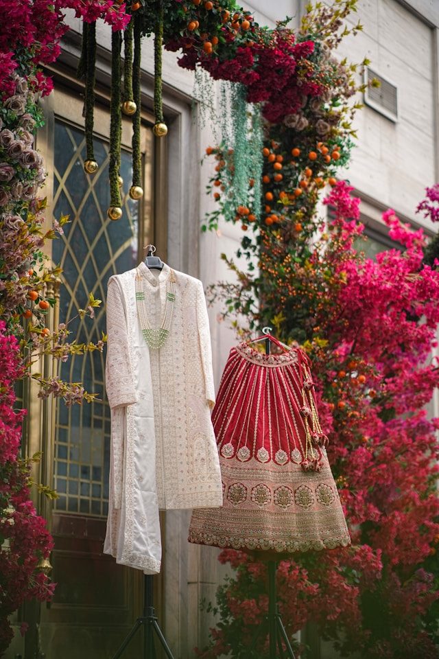 Indian wedding couture — sherwani and bridal lehenga amid floral installation